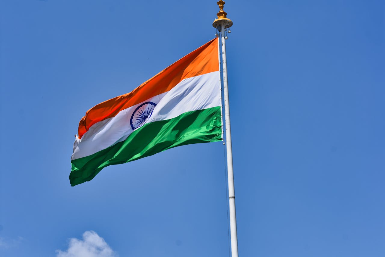 The Indian national flag waving against a clear blue sky symbolizes patriotism and national pride.