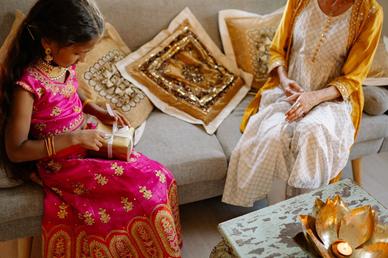 Young girl in traditional attire receiving a gift during Diwali celebration.